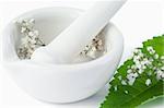 Mortar and pestle with flowers and leaf against a white background