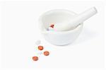 Mortar and pestle with pills against a white background