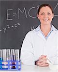 Smilling scientist stanting in front of a blackboard