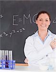 Smilling scientist standing in front of a blackboard looking at the camera