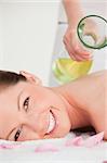 Portrait of a smiling woman having massage oil versed on her back