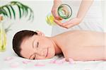 A woman eyes closed getting massage oil on her back in a spa