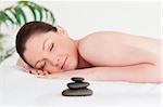 Red-haired woman lying on her belly in a spa with massage stone next to her