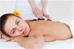 Close up of a delighted woman having a hot stone massage while looking at the camera