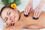 Close up of a smiling woman enjoying a hot stone massage in a spa