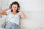 Charming brunette listening to music in her living room