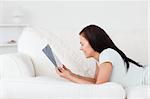 Relaxed woman on a sofa reading a book in her living room