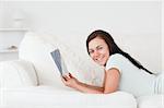 Relaxed woman on a sofa holding a book while looking at the camera