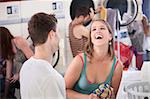 Happy young woman with boyfriend laughs out loud in the laundromat