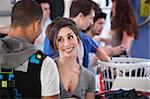 Young Caucasian lady with boyfriend grins in laundromat