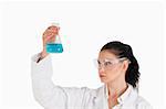 Dark-haired scientist conducting an experiment while looking at a blue flask