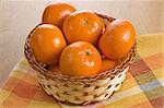 Ripe fresh tangerine in wicker basket on wooden background