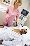 Nurse Checking On Patient Lying On Hospital Bed