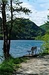 A solitary wooden bench facing the calm waters of a beautiful Alpine lake