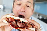 Middle Aged Man Eating A Bacon Sandwich