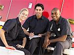 Three paramedics chatting and doing paperwork, sitting by their