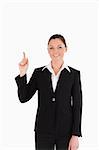 Cute woman in suit pointing at a copy space while standing against a white background