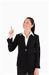 Beautiful female in suit pointing at a copy space while standing against a white background