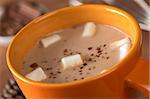 Hot chocolate with marshmallows in orange cup (Selective Focus, Focus on the marshmallows in the middle of the hot chocolate)