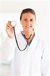 smiling doctor showing stethoscope looking into the camera in her surgery