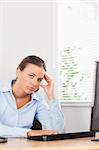 A businesswoman is holding her head in an office