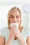 Woman taking in smell of coffee with eyes closed in the kitchen