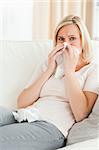 Portrait of a sick woman blowing her nose in her living room