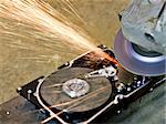 grinder working on open hard drive. Many sparks are flying away. rusty background