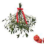 Mistletoe with berries and tied with a red bow with christmas baubles to one side, isolated over white background.