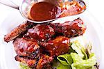 A dish of chicken wings with sauce and greens.