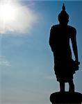 Silhouette Buddha image against the sun with blue sky