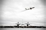 A picture of two planes in grey one on the apron and the second blurry one taking off