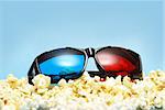 A pair of sleek 3D glasses rests on top of a pile of fresh popcorn.