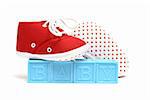 The word baby is isolated on white with a pair of red shoes.
