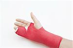 Right hand bandaged in red plaster to support the healing process of broken bone. There is loads of copyspace as the backround is white