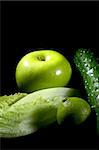 group of green vegetables and fruits over black background