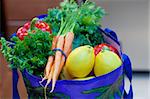 Fresh vegetable, fruits, and herbs in a grocery bag in the kitchen