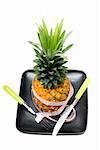 pineapple on a black plate with tape meter,knife and fork isolated on white background