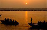 A stunning sunrise looking over the holiest of rivers in India. The Ganges. Silhouettes of boats dapple the horizon.