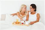 Woman giving a piece of croissant to her boyfriend in their bedroom