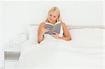 Lovely woman reading a book in her bedroom