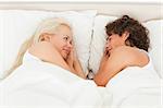 Couple lying while looking at each other in their bedroom