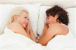 Portrait of a smiling couple lying while looking at each other in their bedroom