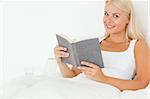 Cute woman holding a book in her bedroom