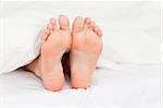 Close up of feminine feet in a bed
