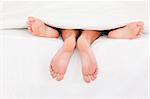 A couple's feet in a bed