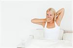 Woman yawning on her bed looking away from the camera