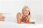 Smiling woman on the phone with a notebook in her bedroom
