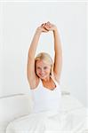 Portrait of a lovely woman stretching her arms in her bedroom