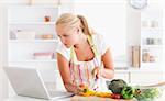 Woman using a laptop to cook in her kitchen